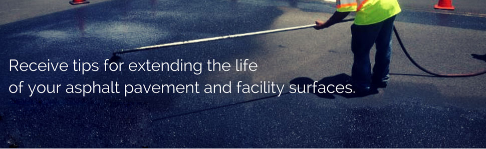 Worker sealcoating an asphalt pavement